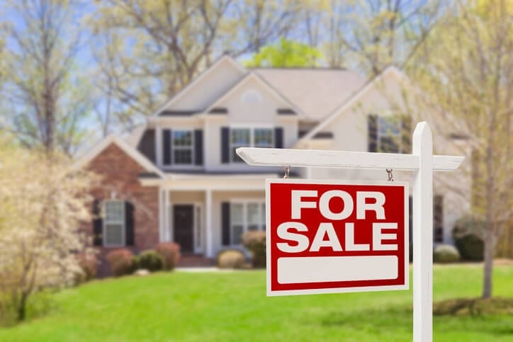 A For Sale sign in front of a house.